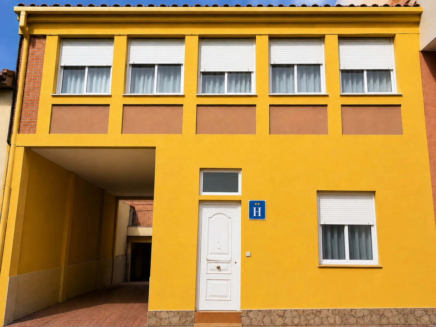 Fachada amarilla con puerta blanca del Hostal Matilda's en la Calle Cuéllar 9 de Segovia