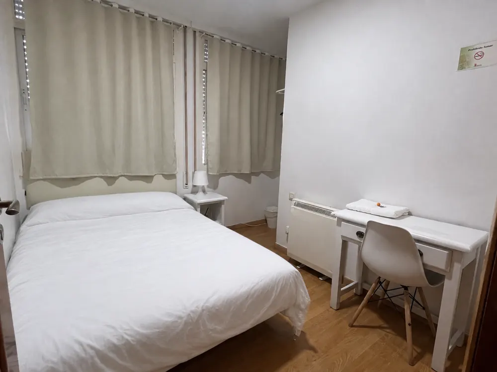 Habitación Fuencisla del Hostal Matilda's en Segovia: cama de matrimonio, escritorio y ventanas